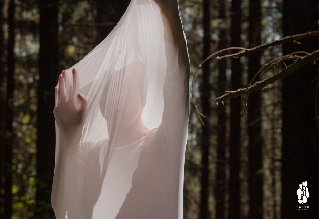 Person behind a white protective fabric in a forest