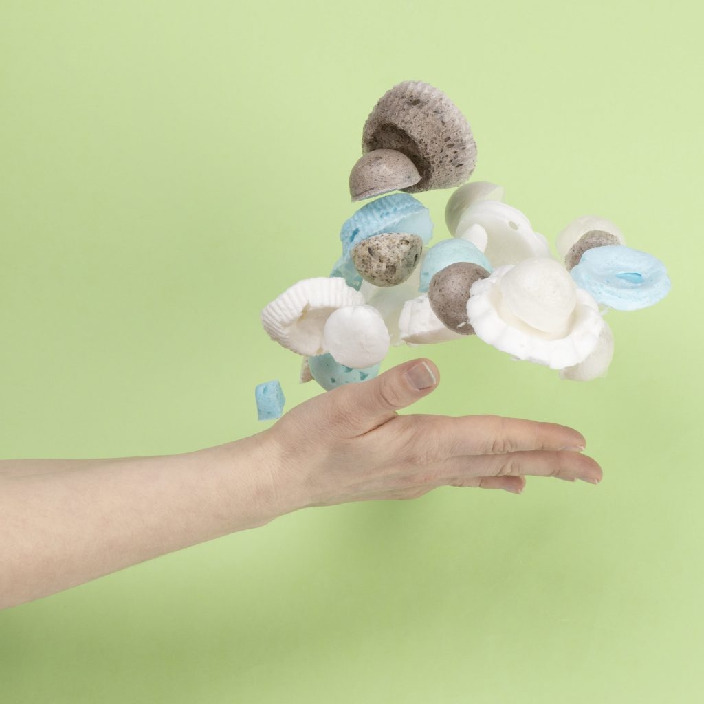 Hand throwing toilet paper foam samples in the air on a green background.